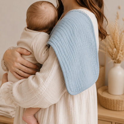 Bébé contre l'épaule d'une femme, une serviette bleu pastel en mousseline protège l'épaule de la mère.